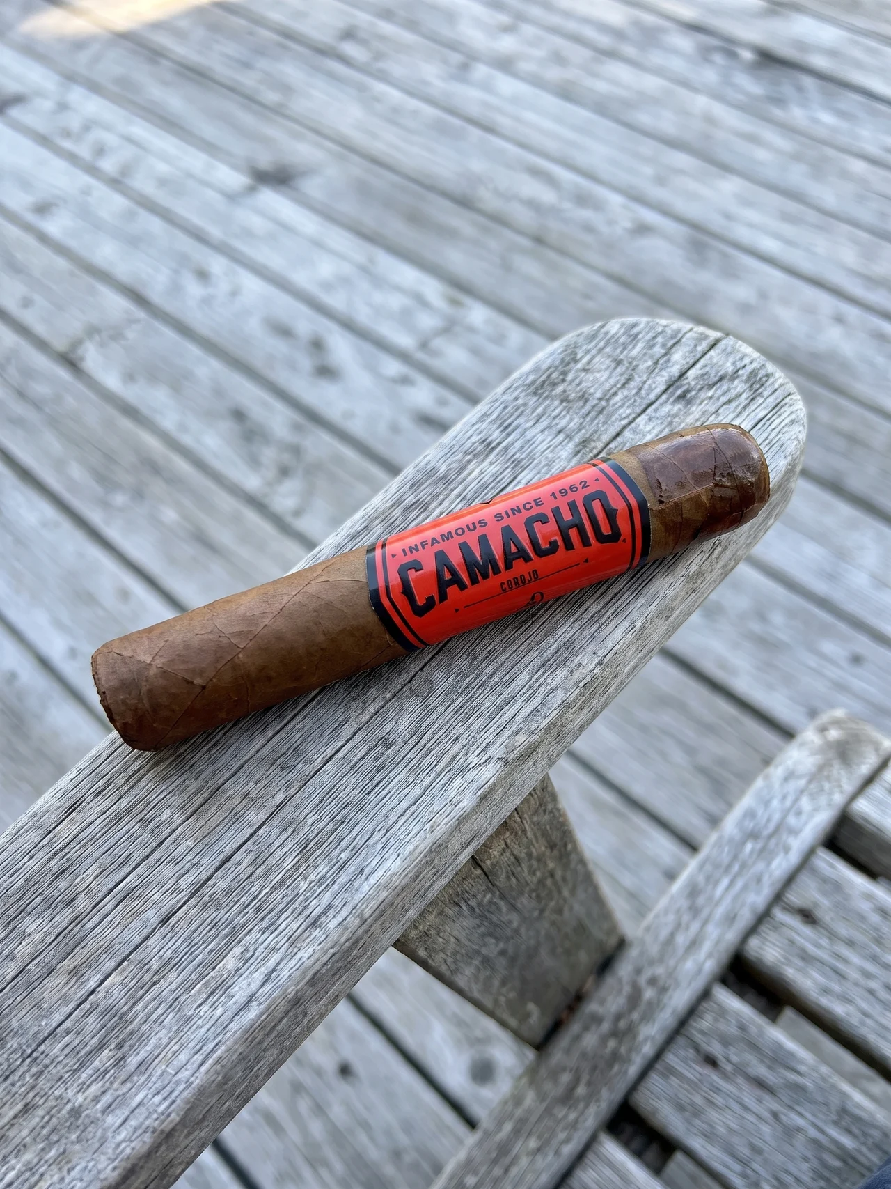 CAMACHO COROJO ROBUSTO 5×50 held in hand on the porch