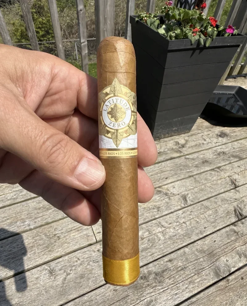Hand holding the Latitude Zero Los Rios gordo over weathered deck boards