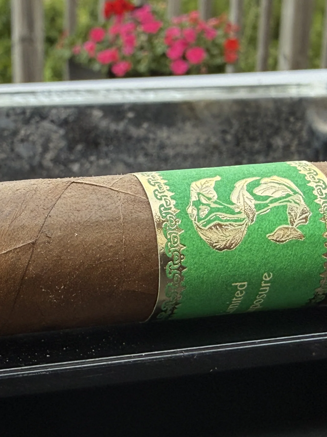 Matilde Limited Exposure No. 3 resting on an ashtray with flowers in the background