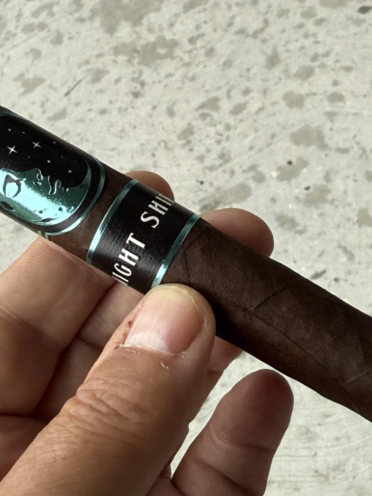 Infinity Night Shift Toro held in hand, black and teal Night Shift band in view