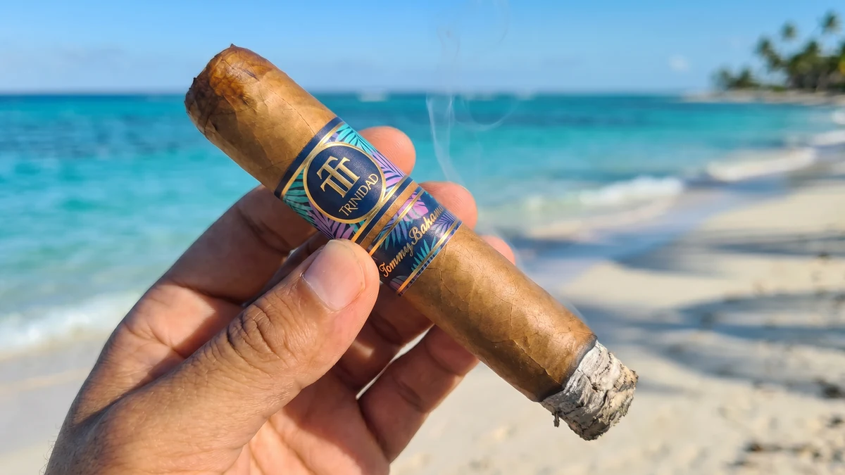 Hand holding the TRINIDAD X TOMMY BAHAMA ISLAND COLLECTION BREEZE TORO 6×54 at the ocean with a half-inch ash